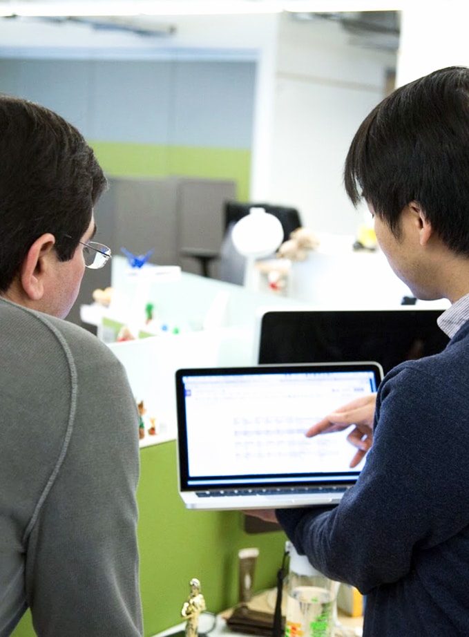 A student points out a key result on a laptop screen to a colleague