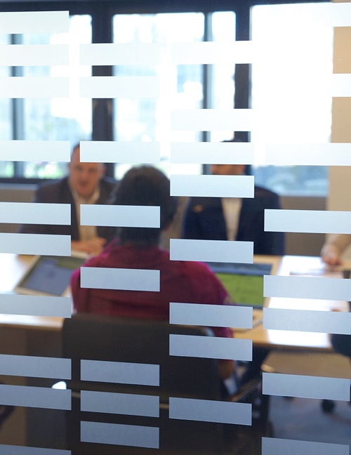 Board of Directors have a meeting in a glass-sided conference room