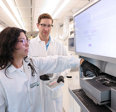 Two scientists work on a gene sequencing machine
