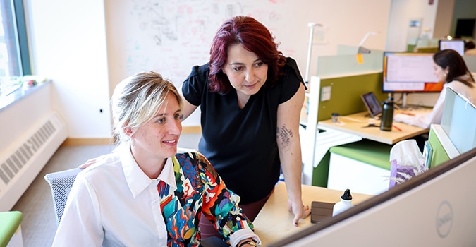 Two women consider a computer screen in an office setting
