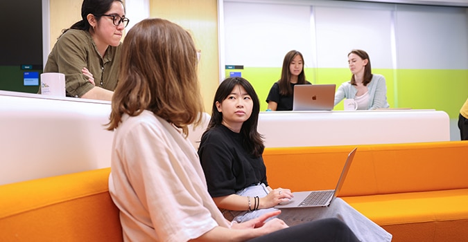 A group of five NYGC employees sit in a common area with laptops