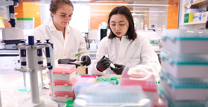 Two scientists consider a pipette in a lab at NYGC
