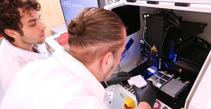 Two scientists use a genomic sequencing machine developed at NYGC