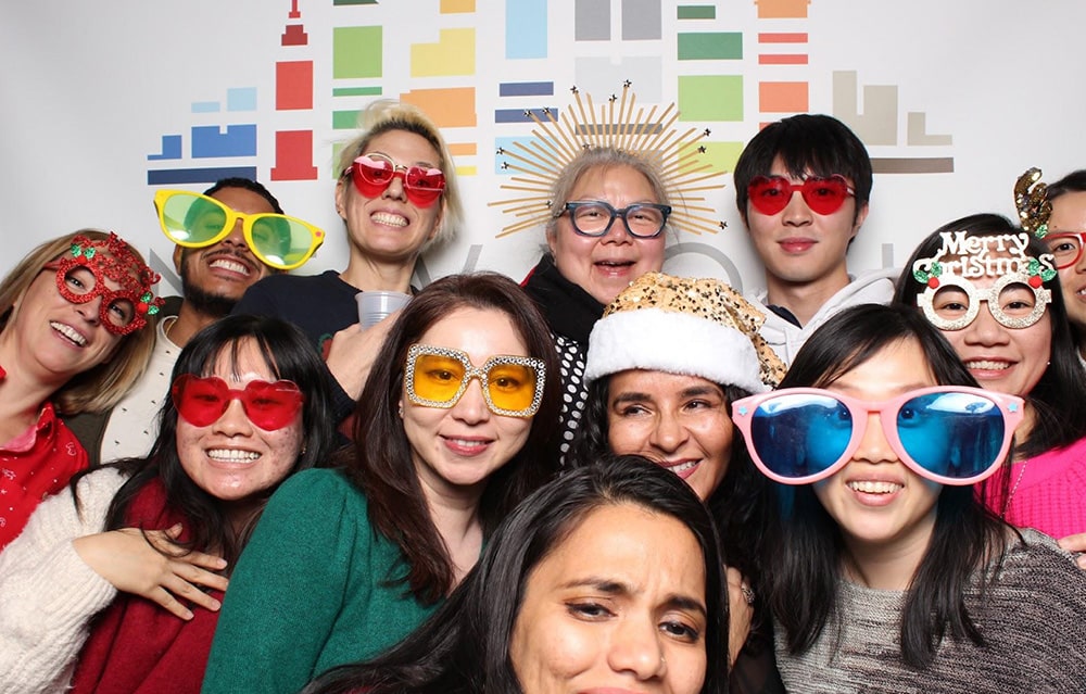 A group of NYGC employees pose in silly glasses at a company event
